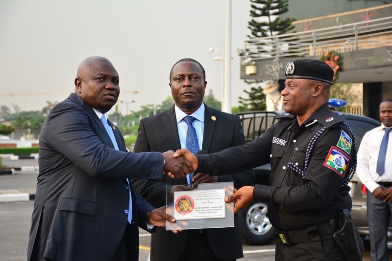 Lagos State Governor, Mr. Akinwunmi Ambode (left), being presented with the Best Security and Safety Conscious award given to the State Government in South Africa by Commander, RRS, ACP Tunji Disu (right) while Permanent Secretary, Office of Chief of Staff, Mr. Abiodun Bamgboye (middle), watches during the handing over of 3 Patrol Vehicles and 45 Power Bikes to the Rapid Response Squad (RRS) at the Lagos House, Ikeja, on Monday, December 5, 2016.